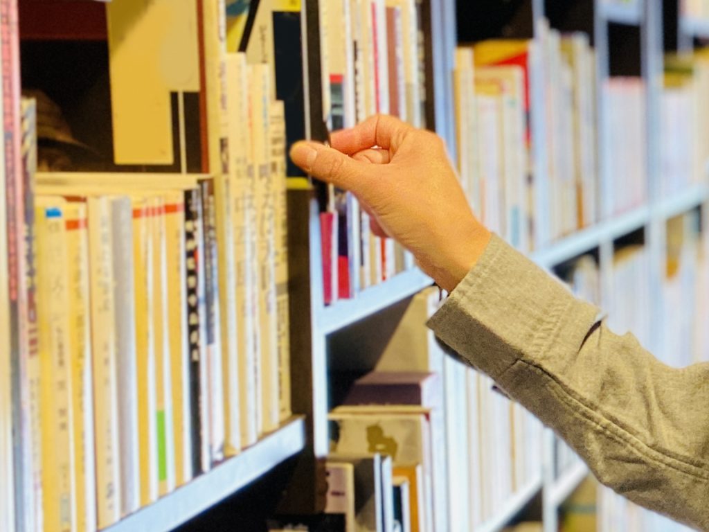 図書館の本に手を伸ばす女性の手